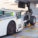 Airplane tow truck hooked up on the front landing gear.